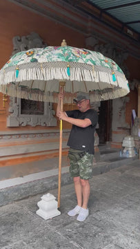 Birdie Parasol featuring exotic bird patterns on a soft white canvas, with handcrafted details and turquoise tassels.